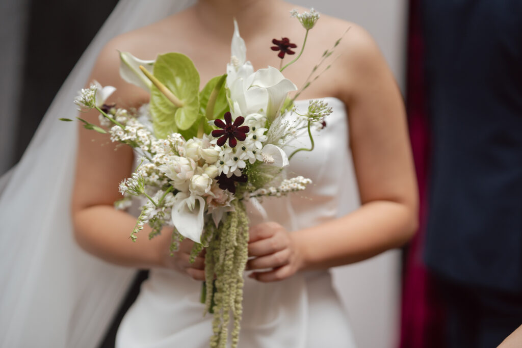 Bride holding a modern wedding bouquet with white and burgundy flowers, styled with a Maticevski satin dress